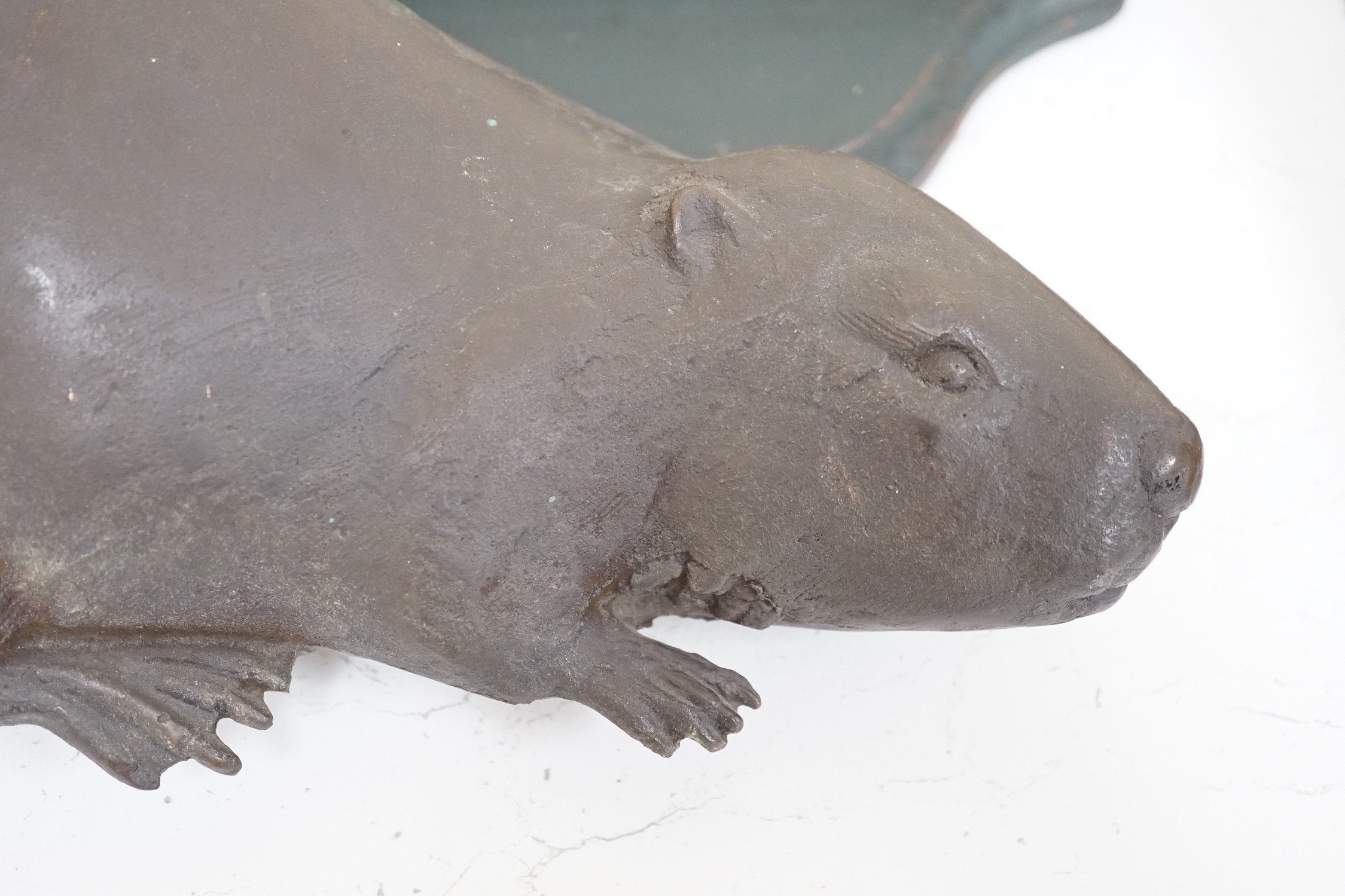 A bronze relief of a beaver and shaped green wall bracket